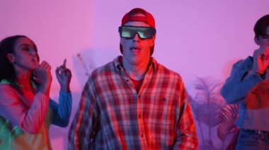 Çeşitli arkadaşlarla sokak dansı pratiği yapan profesyonel break dansçı. Çok kültürlü mutlu insanlar modern dans ederken şık giysiler giyer veya hippi tarzı dans ederler. Neon ışığı. Mutluluk.