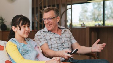 Grandfather and granddaughter together watch interesting entertainment media on TV. Old senior use technology communicate with young generation cross generation gap strengthen family bond. Divergence. clipart