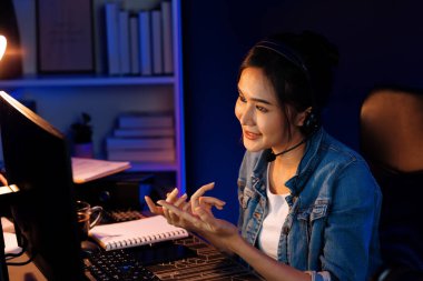 Sunucu kanalı Asyalı etkileyicisi canlı yayında konuşuyor. Sosyal medyada kulaklık takıyor, bilgisayar kaydı yapıyor, dinleyicileri selamlıyor ve Neon Modern Stüdyoları 'nda online olarak koçluk yapıyor. Taktik.