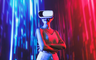 Zeki bir kadın, metaevreni birbirine bağlayan VR kulaklık takan neon ışıklarla çevrili duruyor. Gelecekteki siber uzay topluluğu teknolojisi. Zarif kadın kendinden emin bir şekilde çapraz kol pozu veriyor. Uzağa bak. Halüsinasyon.