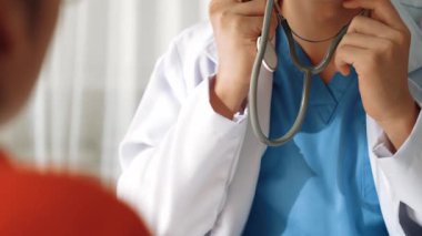 Hasta klinikte ya da hastane ofisinde doktor randevusuna gidiyor. Hastaların nabzını steteskopla kontrol edip risk faktörünü belirleyen doktor semptomları inceliyor. Panorama. Katı.