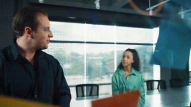 Profesyonel iş adamları yaratıcı pazarlama fikrini modern ofiste tartışırlar. İş adamları cam tahtada yapışkan notlar kullanarak finansal plan üzerinde çalışıyor. Yönlendirici.