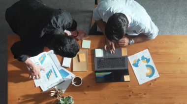 Toplantı masasında dizüstü bilgisayar kullanarak verileri analiz etmek için birlikte çalışan iş ekibinin üst düzey görüntüsü. Kooperatif olarak grup oluşturun grafiğe bakarken tartışın ve beyin fırtınası planı yapın. Cemaat.