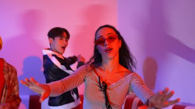 Çok kültürlü bir arkadaş birlikte dans ediyor ve hiphop müziği eşliğinde restoranda ya da kafede pembe neon ışıklı duruyor. Profesyonel sokak dansçıları grubu enerjik hareketler sergiliyor. Mutluluk.