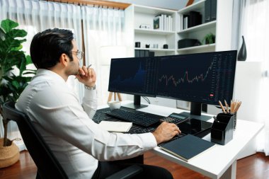 Akıllı tüccar işadamı, modern merkez ofisindeki araştırma pazarında en yüksek kârlı finansal teknolojiye yatırım yaparak bilgisayar üzerinde iki dinamik borsa yatırım ekranını analiz ediyor. Tahmin et..