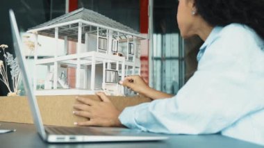 Laptop analizi ev modeli yapısını kullanan İspanyol mimar el mühendislerinin yakın çekimi. Proje yöneticisi dizüstü bilgisayarda yazarken ev modeli inşaatını kontrol ediyor. Tasarım konsepti. Yönlendirici.