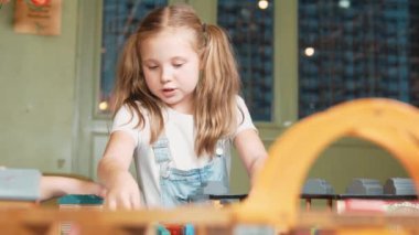 Yaratıcılığı geliştirmek ve geliştirmek için oyuncak oynayan çok kültürlü bir kız. İlkokuldaki oyun odasında araba mankeni tutan çeşitli öğrenciler ara verdiklerinde oturuyorlar. Yaratıcı aktivite konsepti. Etkinlik.