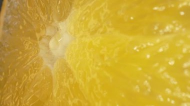 Dilimlenmiş bir portakalın canlı turuncu renginde makro fotoğrafı ve narenciye meyvesinin sulu etinden görülebilir. Portakalın eti dolgun görünüyor. Sıcaklığını gösteriyor. Geliştirilebilir.