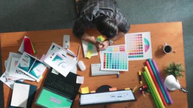 Kulaklıktan müzik dinlerken yetenekli iç dizayn grafiklerinin yukarıdan aşağı havadan görüntüsü. Proje yöneticisi kulaklıkla çalışırken ve rahat şarkılar dinlerken stüdyoda hareket ediyor. Sempozyum.