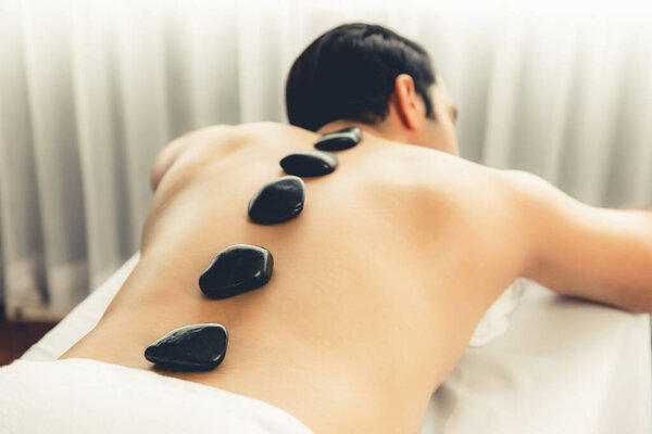 Массаж горячими камнями в спа-салоне на роскошном курорте с дневной легкой атмосферой спокойствия, блаженный клиент, наслаждающийся спа-массажем из базальтового камня скользит по телу с успокаивающим теплом. Quiescent