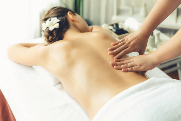 Caucasian woman customer enjoying relaxing anti-stress spa massage and pampering with beauty skin recreation leisure in day light ambient salon spa at luxury resort or hotel. Quiescent