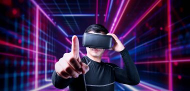 VR gözlüklü profesyonel erkek oyuncu parlayan neon ışıkla oyun oynuyor. Heyecanlı oyuncu artırılmış gerçeklik teknolojisi yeniliklerini kullanarak metaevrene bağlanmayı seviyor. Yaratıcılık.