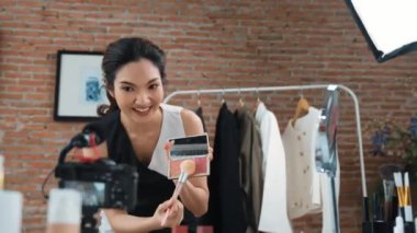 Kadın nüfuzlu kişi canlı yayın yapan video görüntülerini sosyal medya ya da blog üzerinden gözden geçiriyor. Kozmetik stüdyosu ışıklandırmalı mutlu genç kız çevrimiçi pazarlama oturumu yayını için..