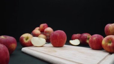 Elmaların makrografisi çeşitli şekillerde sergilenir: bütün, dilimlenmiş ve siyah arka planlı cam bir kase içinde. Her yakın çekim kesme tahtasındaki elmaların kırmızı renklerini yakalar. Geliştirilebilir.