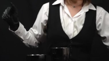 Makrografi, bir barmenin martini bardağına canlı kırmızı bir kokteyl karıştırma sanatına tanık olmak, güzel süslenmiş taze bir biberiye ve parlak siyah bir arka plan. Geliştirilebilir.
