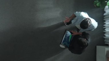 Yöneticinin elinde tablet tutarken yatırımcıyla durduğu ve mali istatistiklere baktığı en düşük bakış açısı. Lider konuşuyor ve tabletteki borsa grafiğinin artması konusunda tavsiyede bulunuyor. Cemaat.