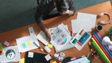 Toplantıda tasarımcı yazma ve logo grafiği tasarlamanın en üst görünümü. Renkli paletler üzerinde çalışan iş adamlarının yakınlaşması ve masaya kağıt ve ekipman ile yapışkan notlar yazmak. Sempozyum.