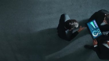 Profesyonel iş adamının yukarıdan görünüşü bir ekibe katıldı ve yönetici müdürle tokalaştı. Akıllı pazarlama ekibi tabletteki yatırım verilerini analiz etmek için birlikte çalışıyor. Müdürlük.