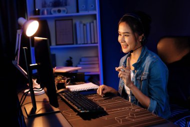 Sunucu kanalı Asyalı etkileyicisi canlı yayında konuşuyor. Sosyal medyada kulaklık takıyor, bilgisayar kaydı yapıyor, dinleyicileri selamlıyor ve Neon Modern Stüdyoları 'nda online olarak koçluk yapıyor. Taktik.