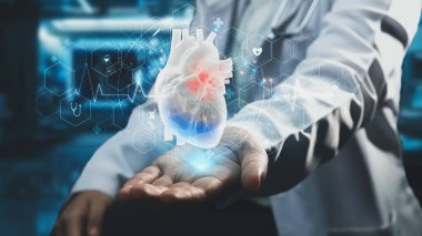 Akıllı doktorların oturduğu ve laboratuvarda elinde kalp hologramının bulanık bir şekilde yüzdüğünü gösteren yakın plan. Sağlık çalışanı teşhisi koydu ve kalp ameliyatına hazırlanıyor. Teknoloji. İyileştirici.