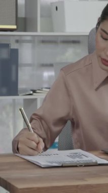 Ofiste çalışan ve dizüstü bilgisayar yazan hevesli bir iş kadını. Masasında oturmuş laptopla çalışan güzel bir ofis hanımı..