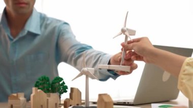 Temiz enerji ve ahşap blokla temsil edilen yel değirmeni modeli ekoloji evini sembolize ediyor. Yeşil enerji grafiği, dizüstü bilgisayarda çalışan iş adamının gelecekte ne yapacağına karar vermesi için dağıtıldı. Tanımlama.