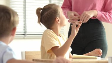 Beyaz bir çocuk ödevlerini yaparken ve açıklama dinlerken güzel bir öğretmen sınavı açıklıyor. Sınıfta not alırken ya da kağıda cevap yazarken öğretmenine bakan sevimli bir çocuk. Pedagoji.