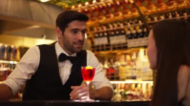 Barmen lüks tezgah barında güzel misafirler için çiçeklerle süslenmiş karışık votka kokteyli servis ediyor. Mükemmel canlı renk sunumu. Atmosfer gece kulübünü ön plana çıkarıyor. Vinosity.