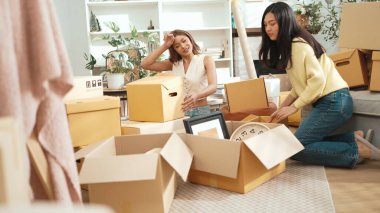 İki kız yeni eve taşınıyor ve oturuyorlar ve kutuları açıyorlar. Ev arkadaşı karton kutuyla çevrili oturma odasında konuşurken dekorasyonu kutudan çıkarıyor. Yeniden yerleştirme. Myrmidon.