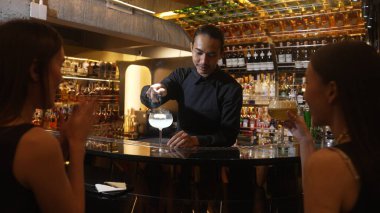 Asyalı akıllı barmen votka bardağını karıştırdı. Çiçek, lüks tezgah barında özel içki yapan güzel müşteriye servis edildi. Ferahlatıcı alkol gece hayatı lüksü. Vinosity.