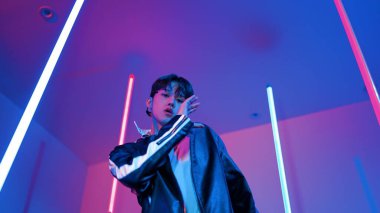 Profesyonel sokak dansçısının sıradan kıyafetlerle kameraya baktığı alçak açılı kamera. Stüdyoda mor ışık altında dururken şehirde pop müzik yapan yetenekli bir sanatçı. Kapatın. Mutluluk.