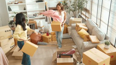 Taşınırken karton kutu taşırken birlikte dans eden mutlu çiftin üst görüntüsü. Çekici oda arkadaşı arkadaşına gösterirken kutudan bez toplarken müziğe yönelmiş. Yeniden yerleştirme. Myrmidon.