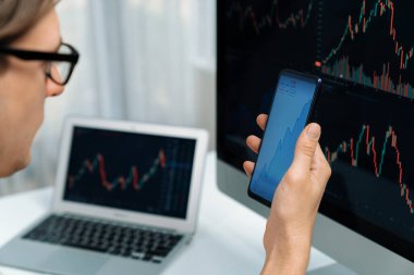 Akıllı borsa yatırımcıları ekranda akıllı telefon ile piyasa borsasını işaret ederek dizüstü bilgisayarın yanı sıra en yüksek dinamik yatırım oranını göstererek, modern işyerindeki veri planlamasına odaklanıyorlar. Bireysel.
