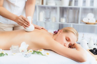 Sıcak bitkisel top spa masaj vücut tedavisi, masör kadın vücuduna nazikçe şifalı bitki torbası bastırıyor. Aromaterapi dinlenme sükuneti ve sükuneti kaplıca salonundaki atmosferi aydınlatıyor. Sessiz.