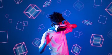 Geometrik şekillerde süzülürken mavi arka planda duran zeki çocuk. Afrikalı bir adam oyun oynuyor, VR gözlük takıyor ve sıradan bir gömlek giyiyor. Gelişmiş gerçeklik teknolojisi yenilik kavramı. Yaratıcılık.