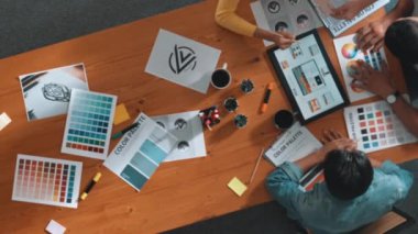 Proje yöneticisi renk paletleri seçerken tasarımcının tablete baktığı yukarıdan aşağıya hava görüntüsü. Profesyonel grafik tasarımının en üst görüntüsü ve logoya bakın. Yetenekli ekip grafikleri seçiyor. Sempozyum.