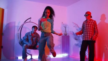 İspanyol hipster renkli kıyafetler giyer ve serbest stil müziğe el sallar. Profesyonel break dansçı neon ışıklarıyla ve modern stüdyo arkadaşlarıyla coşkuyla dans ediyor. Mutluluk.