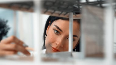 Ev modeli yapısını kendinden emin bir şekilde kontrol etmeye odaklanan genç, güzel, beyaz, yetenekli mimar mühendisinin yakın çekimi. Yaratıcı ve profesyonel tasarım konsepti. Portre. Tertemiz..