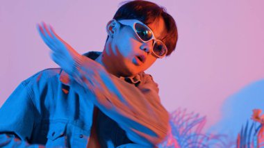 Asyalı sokak dansçısının neon ışıkla pop müziğe geçişine yakın çekim yaparken çeşitli arkadaşlar oturuyor ve performansı destekliyor. Profesyonel sanatçı stüdyoda dans figürleri yapıyor. Mutluluk.