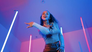 Latin dansçıların kameraya bakıp şehrin pop müziğiyle dans ettiği düşük açılı kamera. Profesyonel çekici hipster, mor veya neon ışıklı hip hop şarkısına geçiyor. Şık bir kumaş. Mutluluk.