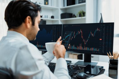 Elinde telefon dinamiğine odaklanan kahve fincanı tutan borsa yatırım ekranı veri analizini karşılaştırarak iç işlerinde yüksek kârlı finans teknolojisi pazarına yatırım yapıyor. Tahmin et..