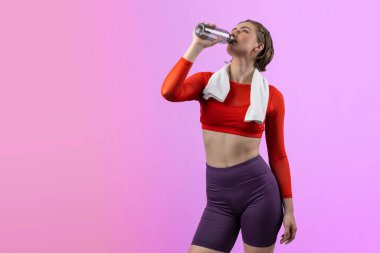 Vücut uzunluğunun tamamı atletik ve sportif genç bir kadını havluyla ve içme suyuyla izole edilmiş arka planda egzersiz yaparken çekilir. Sağlıklı aktif ve vücut bakımı yaşam tarzı.