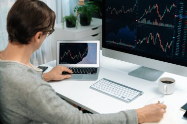 Bilgisayar ve dizüstü bilgisayarı kullanarak, çalışma masasındaki dinamik artırılmış borsa grafiğinin en yüksek kar değerini araştıran bir tüccar, modern ofisteki ekrandaki döviz kuru değerini analiz ediyor. Bireysel.