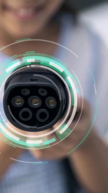 Kameranın önüne odaklanmış EV şarj cihazı fütüristik çevre dostu enerji altyapısı pictogram hologramını gösteriyor. EV araba şarjı sürdürülebilir güç için yenilenebilir enerji kullanıyor. İnceleyin