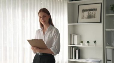 Klinikteki dost canlısı psikolog kadın. Profesyonel portresi. Kameraya bakıp psikolog muayenehanesine bakıyor. Tecrübeli ve kendinden emin psikolog.