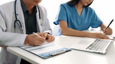 Hastane masasında birlikte çalışan ve tıbbi tedavi planlayan çeşitli profesyonel sağlık görevlileri. Takım çalışması başarılı hastalıklara ve hastalıklara yol açar. Ağır çekim. Katı.