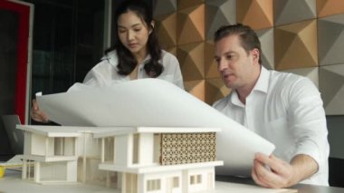Profesyonel mimar mühendis takım tasarımı ve proje planı kullanarak ev hakkında tartışmalar. Proje yöneticisi, ev inşaatını mimari modeli masaya yerleştirilmiş mühendislere açıklıyor. Yönlendirici.