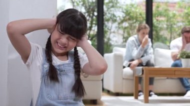 Stresli ve mutsuz genç kız köşeye kıvrılıp kulaklarını kapatarak arka planda ebeveyninin tartışmasını engelliyor. Evde aile içi şiddet ve travmatik çocukluk depresyona dönüşür. Titiz