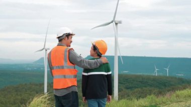 Oğluyla birlikte kırsal kesimdeki bir tepenin tepesinde ya da dağda bir rüzgar çiftliğinde mühendis. Yenilenebilir ve sürdürülebilir enerjinin gelecekteki üretimi için yenilikçi bir ideal. Rüzgar türbininden enerji üretimi.