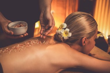 Lüks spa salonlarında sıcak mum ışığında cilt bakımı yaptıran kadın müşteri. Sağlık Spa vücut fırçasında tuz temizleme güzellik tedavisi. Sessiz.